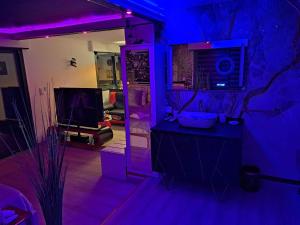 un salon avec des lumières violettes et une télévision dans l'établissement L'Aurore suite de charme, clim jacuzzi, sauna, piscine chauffée cuisine..., à Carpentras