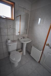 La salle de bains est pourvue de toilettes et d'un lavabo. dans l'établissement Hostal Los Pinos, à Puerto Natales