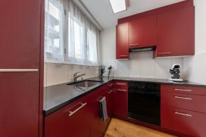 eine Küche mit roten Schränken und einem Waschbecken in der Unterkunft Joe's Apartment am Bolgen in Davos