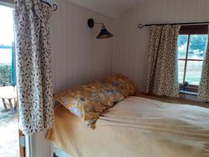 a bed with a pillow in a room with a window at Glamping in Wiltshire in our luxury Shepherds Hut in Chippenham