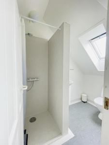 a white bathroom with a shower and a toilet at aday - Charming loft studio in Aalborg