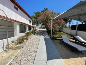 a patio with a bench and an umbrella next to a house at Casa do Moinho de Baixo in Sesimbra