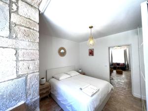 a bedroom with a white bed and a brick wall at La Duchesse - Grand Appartement Au Coeur de Dijon in Dijon