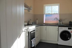 uma cozinha com um fogão e uma máquina de lavar roupa em Remarkable Apartment in Kenmare Ireland em Kenmare