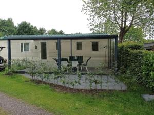 a mobile caravan with a table and chairs in a yard at Stacaravan in De Pol