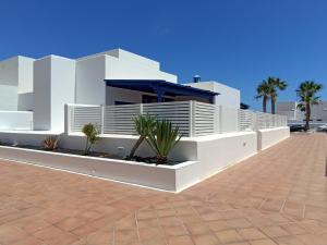 a white house with palm trees in front of it at Casa Rosa in Puerto Calero