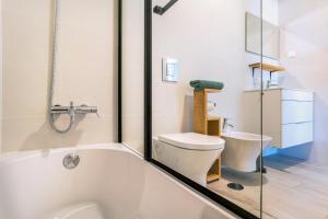 La salle de bains est pourvue d'une baignoire blanche et de toilettes. dans l'établissement Surf & Beach Apartment, à Aljezur