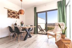 Un comedor con mesa y sillas y una gran ventana. en Surf & Beach Apartment, en Aljezur