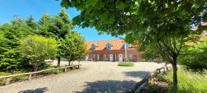 a large brick building with a fence in front of it at Lustrup Farmhouse in Ribe