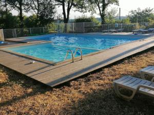a large swimming pool with a wooden deck in a yard at 4-Gîte 4 personnes avec piscine in Saint-Aubin-de-Nabirat