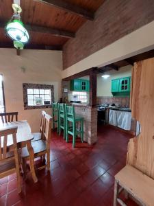 una cocina con armarios verdes, mesa y sillas en Casa Cabana en Unquillo