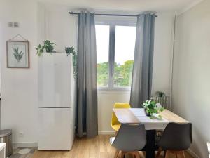 eine Küche mit einem weißen Kühlschrank und einem Tisch mit Stühlen in der Unterkunft Appartement confort in Bois-Colombes