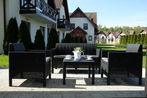 a patio with three chairs and a table with flowers on it at Apartament Blue eye in Żarnowska
