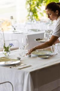 a woman sitting at a table with plates and glasses at La Foresteria Planeta Wine Resort & Beach Club in Menfi