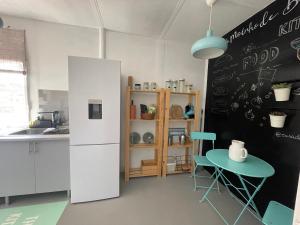 a kitchen with a white refrigerator and a table at Casa do Moinho de Baixo in Sesimbra