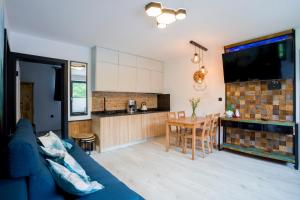 a living room with a blue couch and a kitchen at Apartament Muszyna in Muszyna