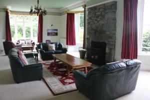 uma sala de estar com sofás e uma lareira de pedra em Cae'r Blaidd Country House em Ffestiniog