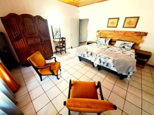 a bedroom with a bed and two chairs in it at Fish eagle Guest Farm in Phalaborwa