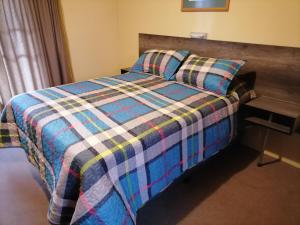 um quarto com uma cama com um cobertor xadrez em Stay a Night em Christiana
