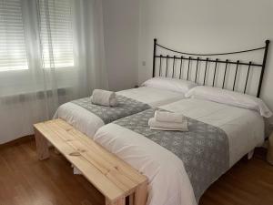 a bedroom with two beds and a wooden bench at Villa de Gredos in Navarredonda de Gredos