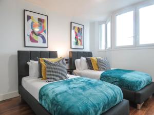 Zimmer mit 2 Betten und blauen Kissen in der Unterkunft Tudors eSuites Five Ways Two Bedroom Apartment in Birmingham