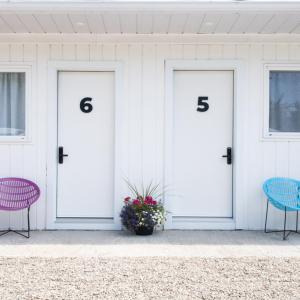 two doors with numbers on them on a house with two chairs at Motel Chelsea in Chelsea