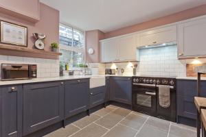 a kitchen with blue cabinets and a stove top oven at Bumble Choo Cottage - Windermere, Lake District in Windermere