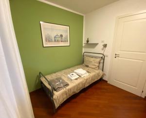 um pequeno quarto com uma cama numa parede verde em Living Rencio: vicino al Centro di Bolzano em Bolzano