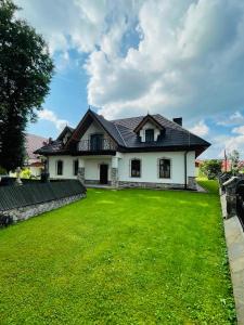 uma casa com um relvado verde em frente em Stara Fara em Jurgów