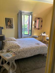 a bedroom with a bed and a window and a table at La Villa des Rosiers in Cricquebœuf