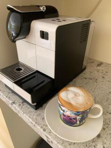 een kopje koffie op een bord naast een koffiezetapparaat bij Alt Mór House Garden Studio-Self Catering Sleeps 2 in Portnoo