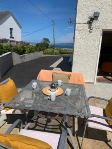 a table and chairs on a patio with a view of the ocean at Alt Mór House Garden Studio-Self Catering Sleeps 2 in Portnoo