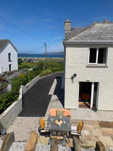 a patio with a table and chairs in front of a house at Alt Mór House Garden Studio-Self Catering Sleeps 2 in Portnoo