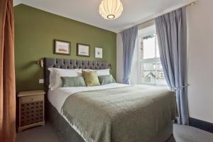 a bedroom with a large bed and a window at Bumble Choo Cottage - Windermere, Lake District in Windermere