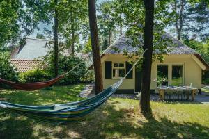 - un hamac en face d'une maison dans l'établissement Cottage Hazenhorst - paradijs aan het bos, à IJhorst