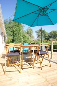 uma mesa e cadeiras de madeira com um guarda-sol azul em LACADUCEE 