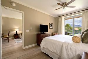 1 dormitorio con 1 cama, TV y ventana en Honua Kai - Konea 310, en Kahana
