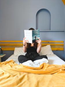 a woman sitting on a bed reading a book at Lamparina Hostel in São Paulo