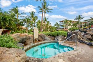 a swimming pool in a resort with rocks and palm trees at Honua Kai - Konea 310 in Kahana