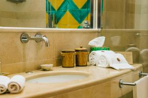 a bathroom with a sink with towels and a mirror at La Foresteria Planeta Wine Resort & Beach Club in Menfi