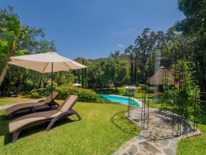 Kilka krzeseł i parasol obok basenu w obiekcie Cubo's Finca La Fuente del Pedregal Casa 2 w mieście Coín
