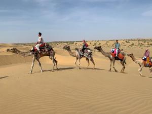 a group of people riding camels in the desert at Hotel Amazing Jaisalmer in Jaisalmer