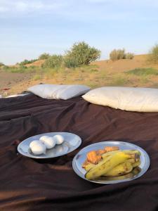 dos platos de comida con huevos y plátanos en una manta en Hotel Amazing Jaisalmer, en Jaisalmer