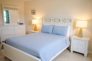 a bedroom with a bed with blue pillows and two lamps at Lantana Resort Barbados by Island Villas in Saint James