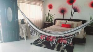 a hammock in a room with a bed and flowers at Casa Campo Emaus in Caucasia