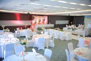 um salão de banquetes com mesas brancas e cadeiras brancas em Ubumwe Grande Hotel em Kigali
