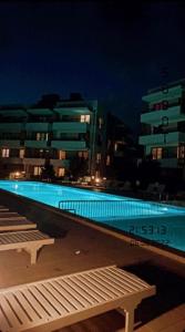 a swimming pool at night with buildings in the background at Apartamenty Wybrzeże Laguna in Ustronie Morskie