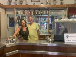 Um homem e uma mulher atrás de um bar. em Albergo Magenta em Casella
