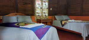 a bedroom with two beds and a table with avertisement at Cabañas Yax-ha in Arroyo Agua Azul