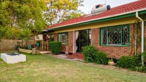 una casa de ladrillo con una ventana verde y un patio en Birdville BNB Guest House, en Gaborone